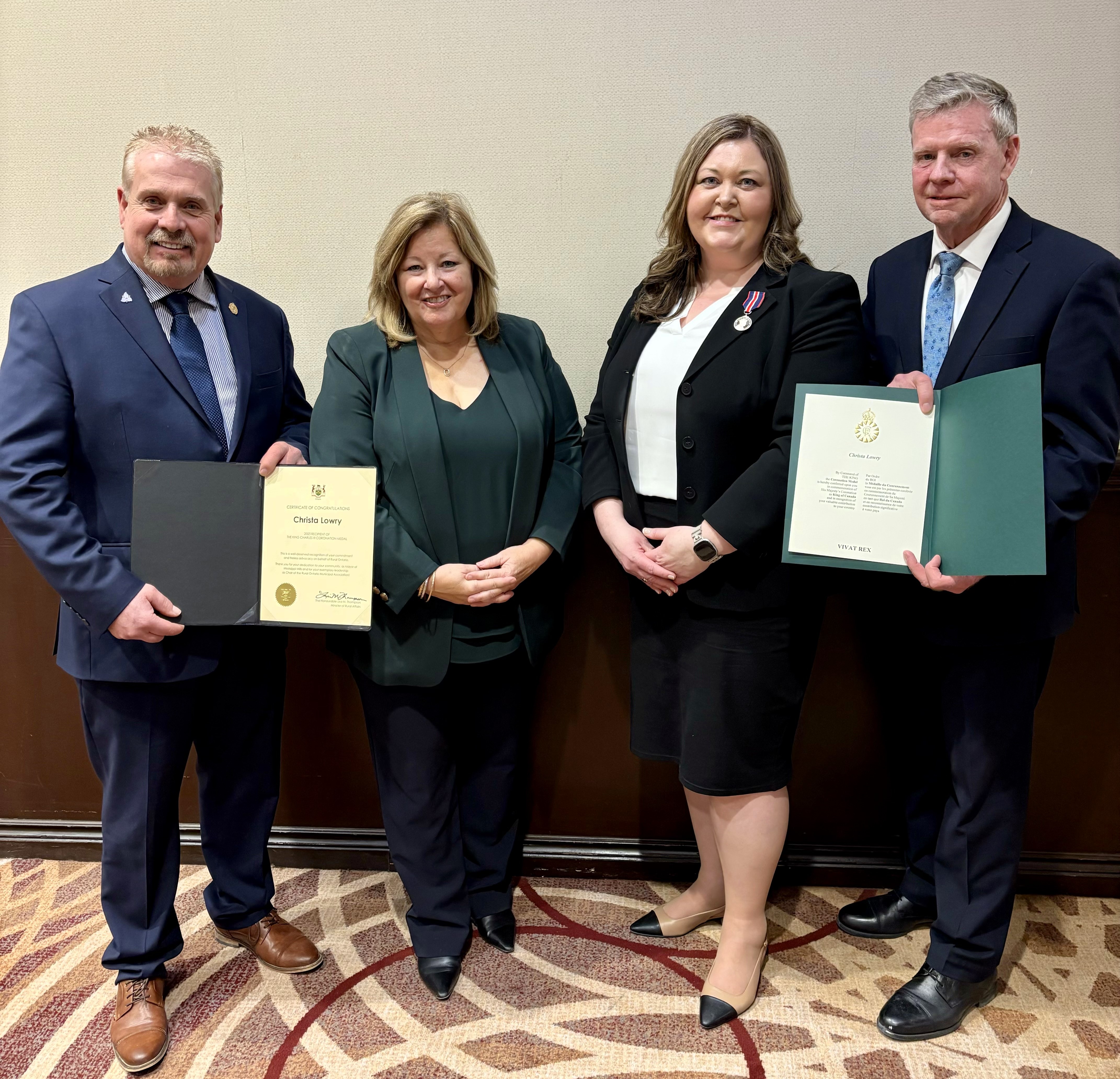 Four people stand holding certificates